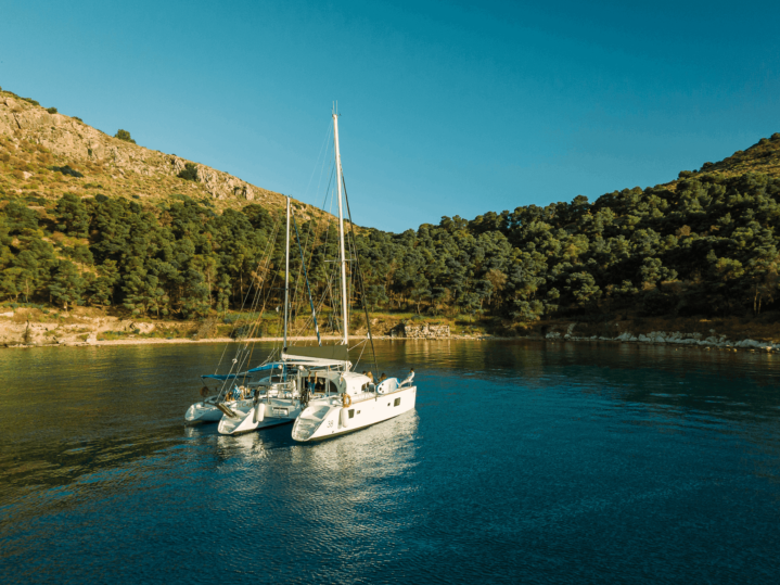 Private half-day catamaran cruise in Nafplio with guests relaxing and swimming in clear waters