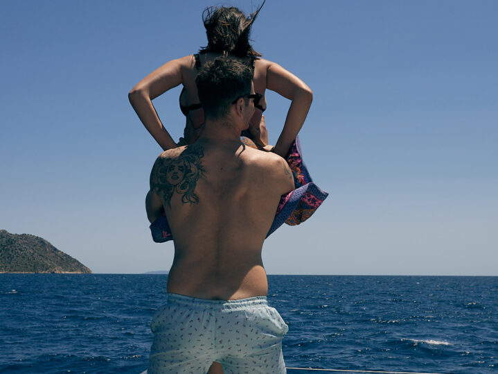 Couple enjoying romantic catamaran cruise swimming together in turquoise waters near Nafplio